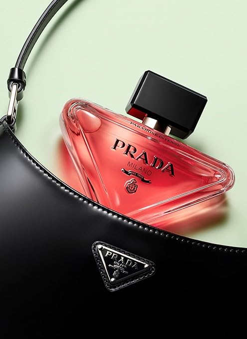 Prada perfume bottle with a black bag on a light green background