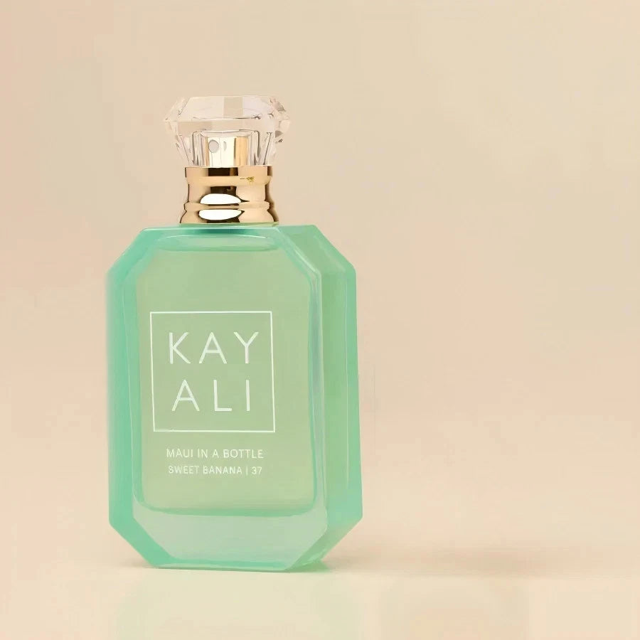 A mint green octagonal perfume bottle with a clear faceted cap and gold collar, labeled 'KAY ALI' on a warm beige background.