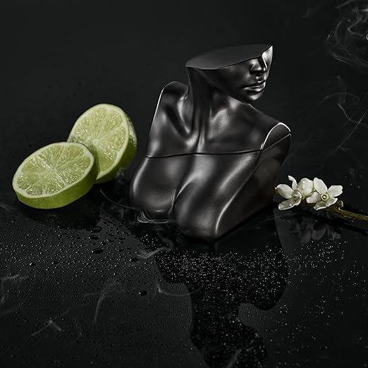 Black abstract sculpture with lime slices and flowers on a reflective surface