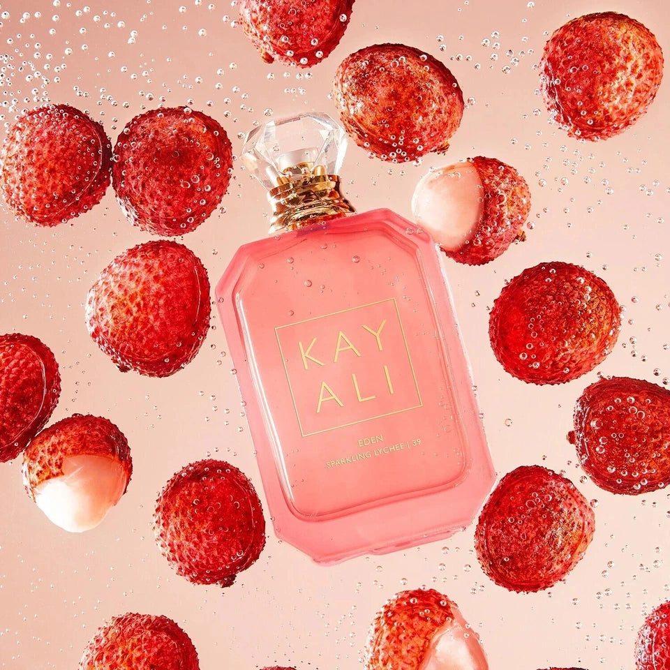 Pink perfume bottle with 'KAY ALI' branding surrounded by strawberries on a pink background