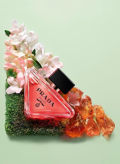 Prada perfume bottle with flowers and grass on a light green background