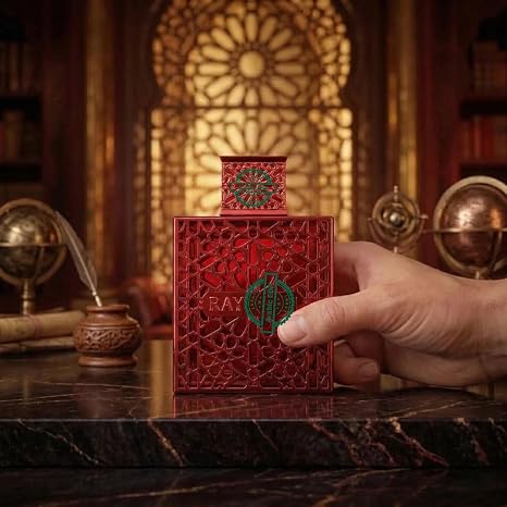 Red perfume bottle with intricate design held by a hand in an ornate room.
