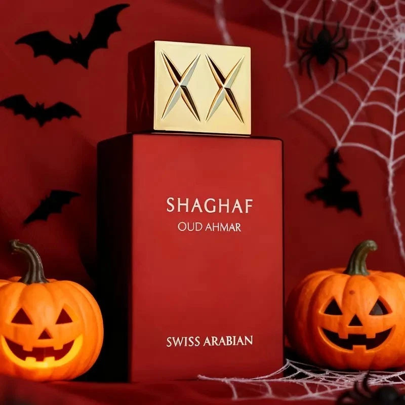 Swiss Arabian Shaghaf Oud Ahmar perfume bottle and box set, styled with Halloween props including jack-o'-lanterns, spiderwebs, and black bats on a red background.