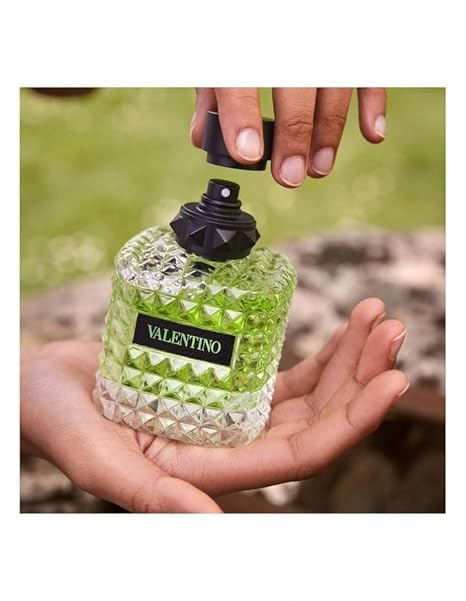 Valentino perfume bottle being held with a blurred green background